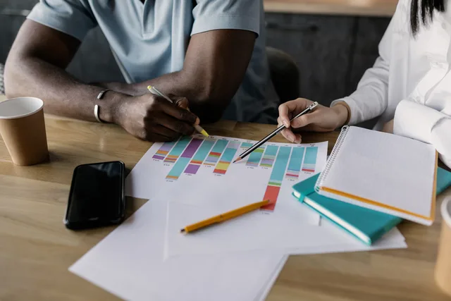 Two professionals planning business strategy using graphs and papers. Check these B2B demand generation 2027 trends before you set budget