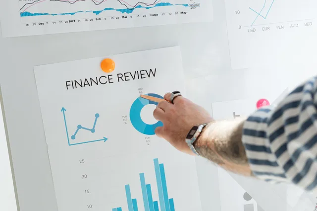 Close-up of a hand pointing to financial charts during a business review. How to assess B2B demand generation agency reviews