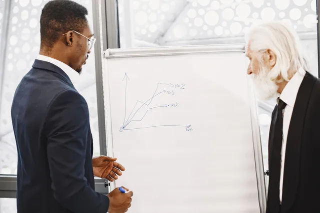 Two businessmen discussing financial charts at an office meeting. How to build B2B buyer personas that reflect real buying decisions